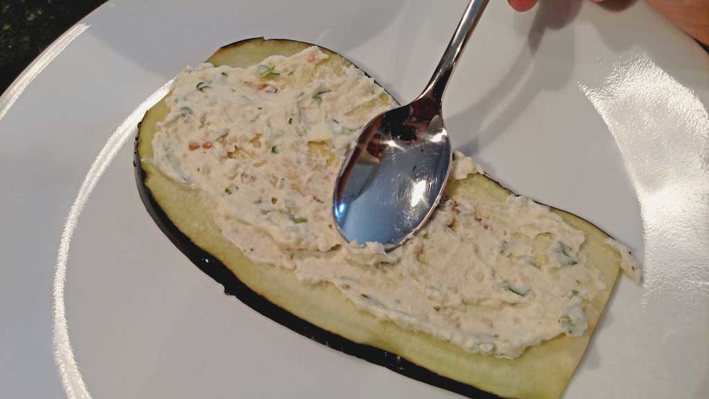 smearing cheese onto eggplant