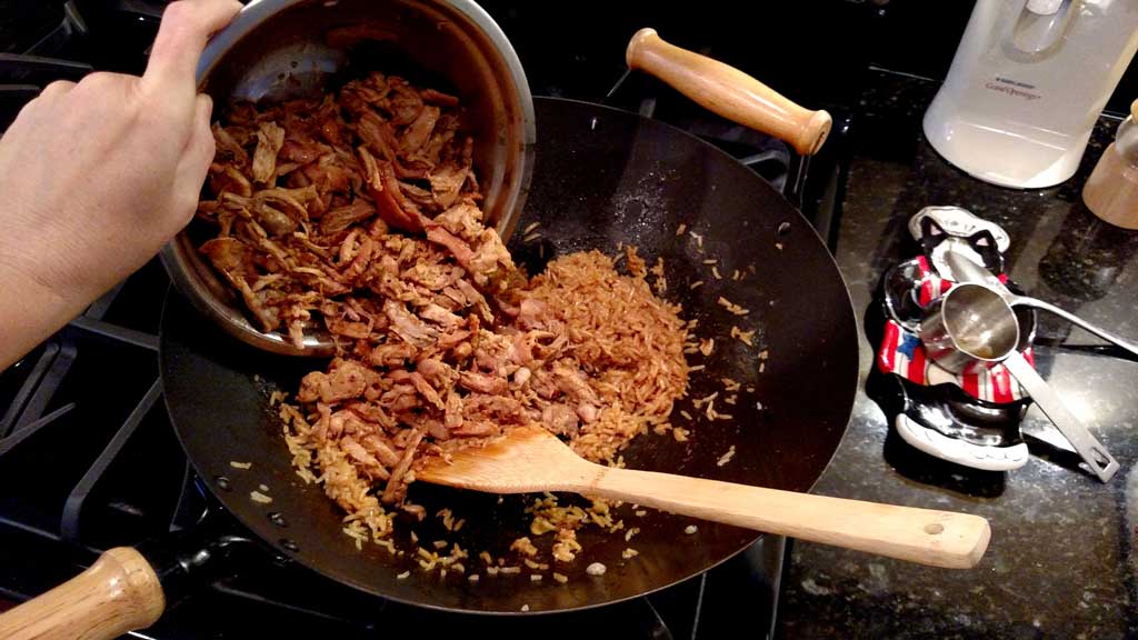 adding orange ginger chicken to wok