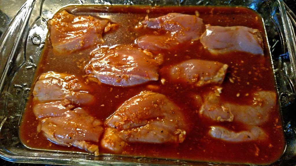 chicken thighs cooking in pan with marinade