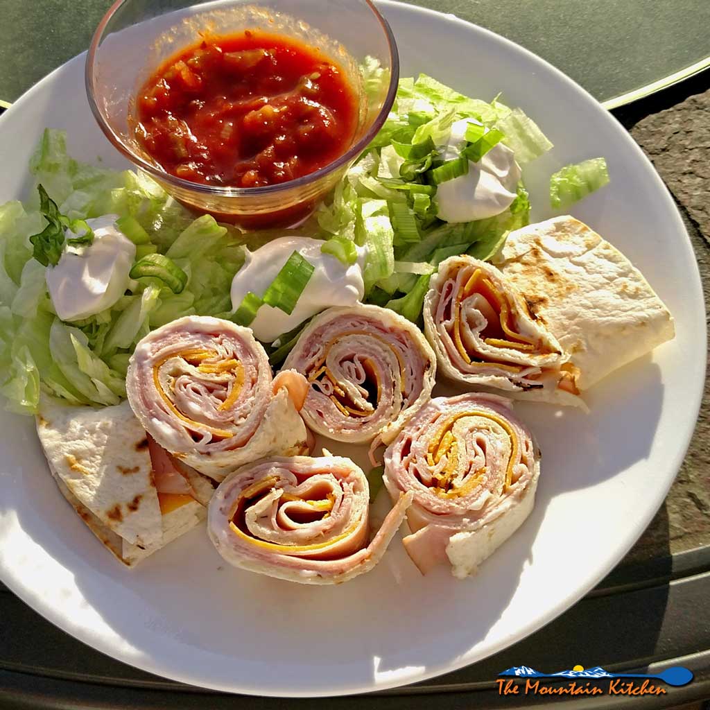 Salsa club rollups are flour tortillas rolled up with ham and cheese; sliced into mini rolls, served with shredded lettuce, salsa, sour cream and chives. | TheMountainKitchen.com