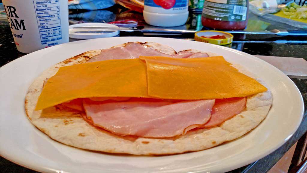 Salsa club rollups are flour tortillas rolled up with ham and cheese; sliced into mini rolls, served with shredded lettuce, salsa, sour cream and chives. | TheMountainKitchen.com