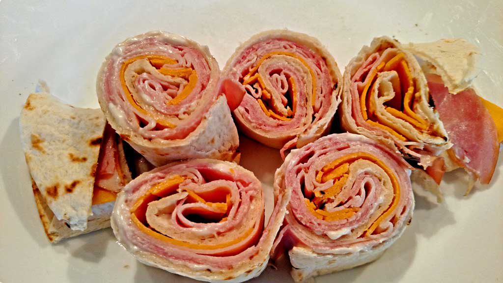 Salsa club rollups are flour tortillas rolled up with ham and cheese; sliced into mini rolls, served with shredded lettuce, salsa, sour cream and chives. | TheMountainKitchen.com