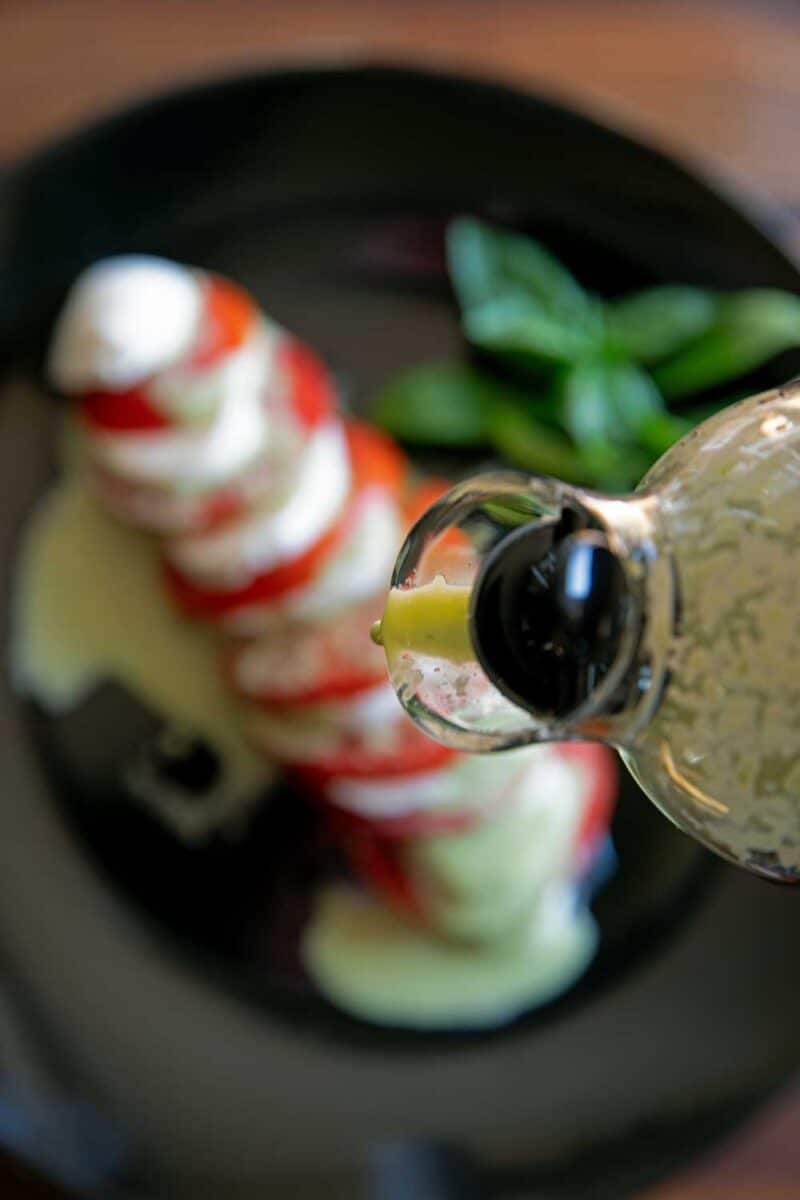 drizzling creamy basil vinaigrette over caprese salad