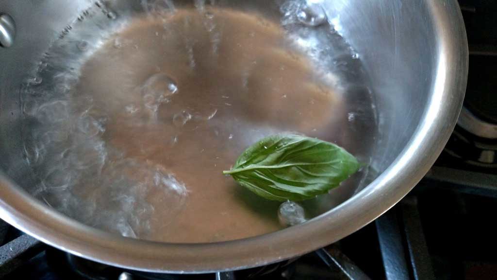 pot of boiling water with basil leaf