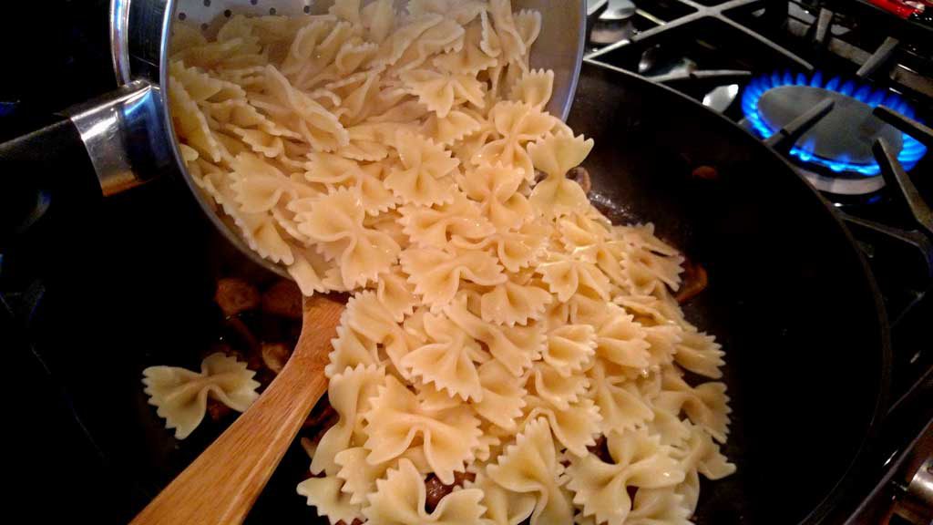 pouring pasta into pan