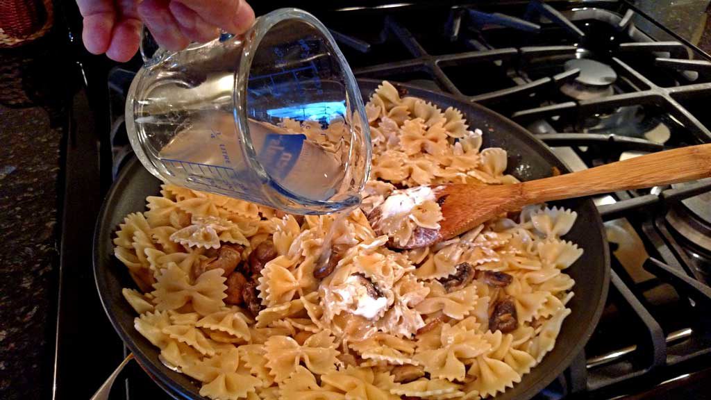 pouring pasta water into pan