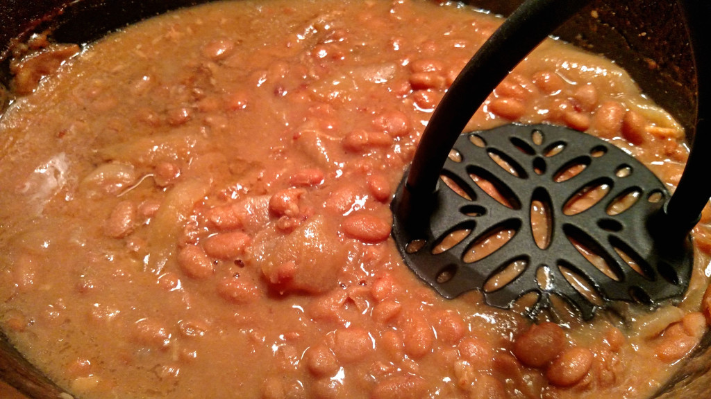mashing refried beans with potato masher