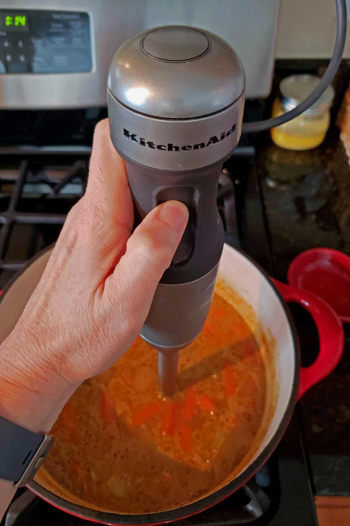 Blending the soup with an immersion blender.