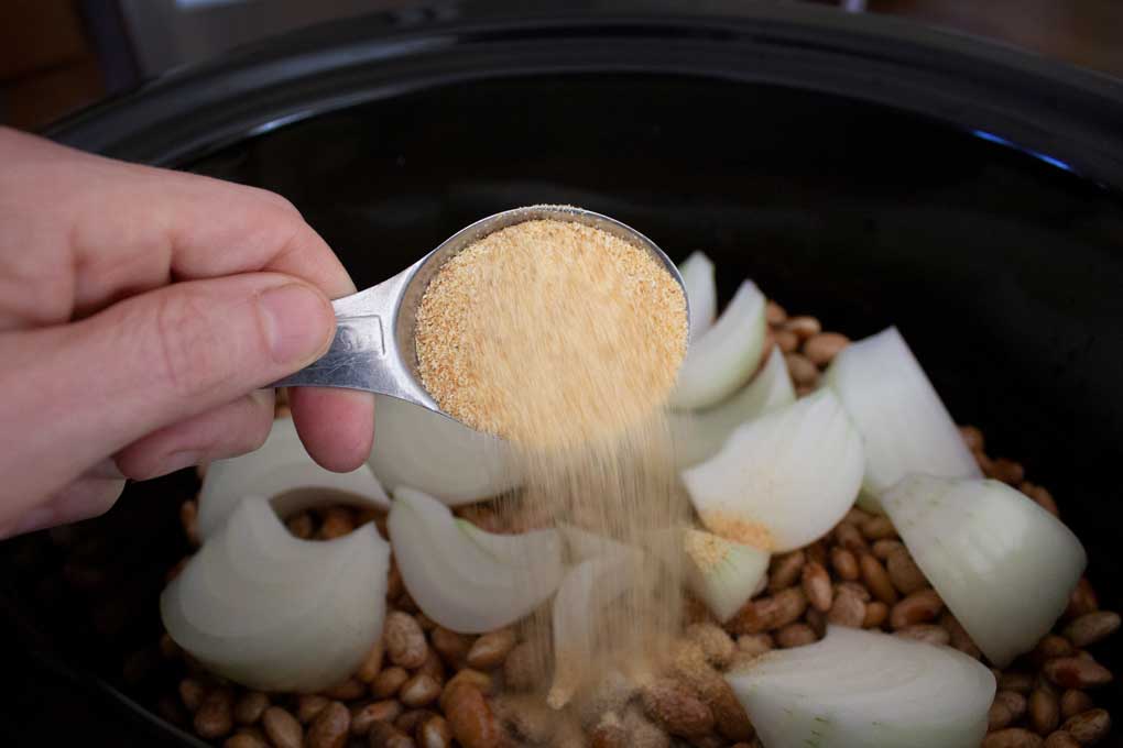 adding garlic to crock-pot of beans