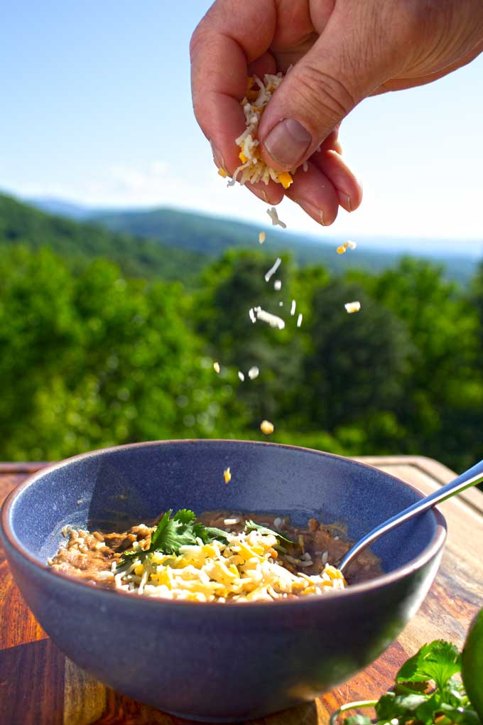sprinkling cheese on beans with mountain view