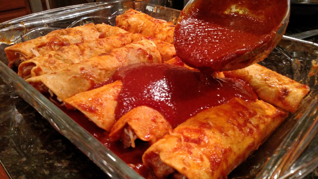 pouring sauce over steak and refried bean enchiladas