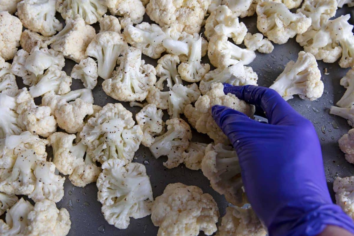 tossing cauliflower on sheet pan