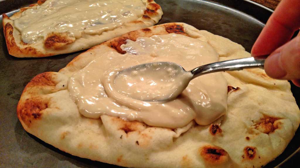spreading the Alfredo sauce out with a spoon