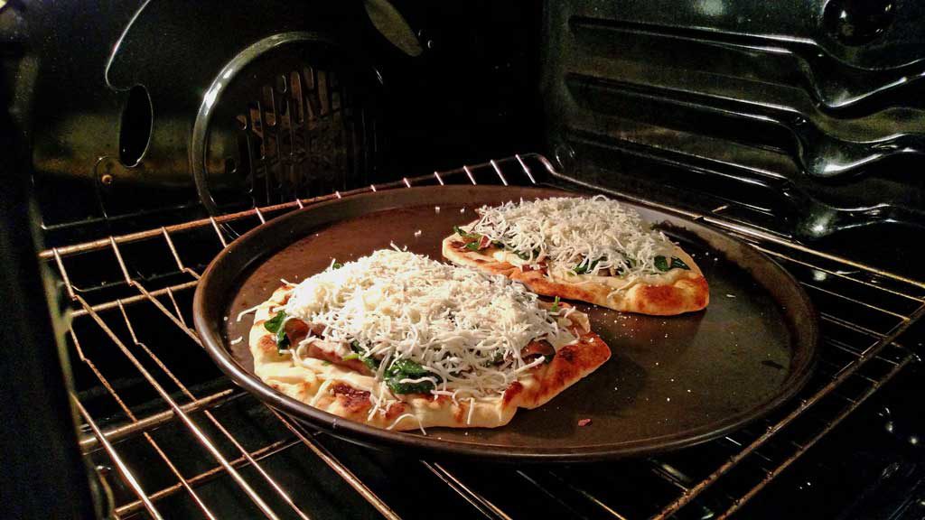 mushroom spinach Alfredo flatbread pizza in oven