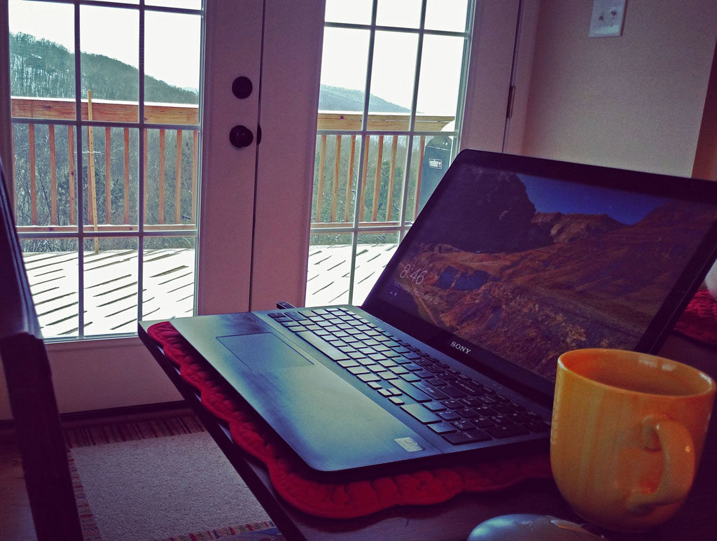 laptop on table with snow outside window