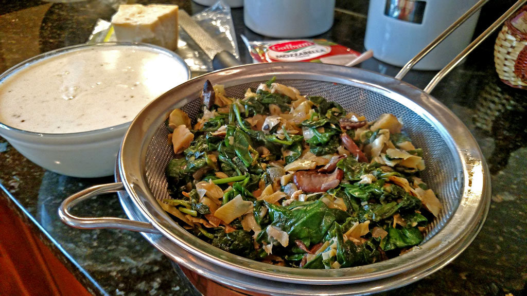 Spinach, artichokes and mushrooms draining in sieve