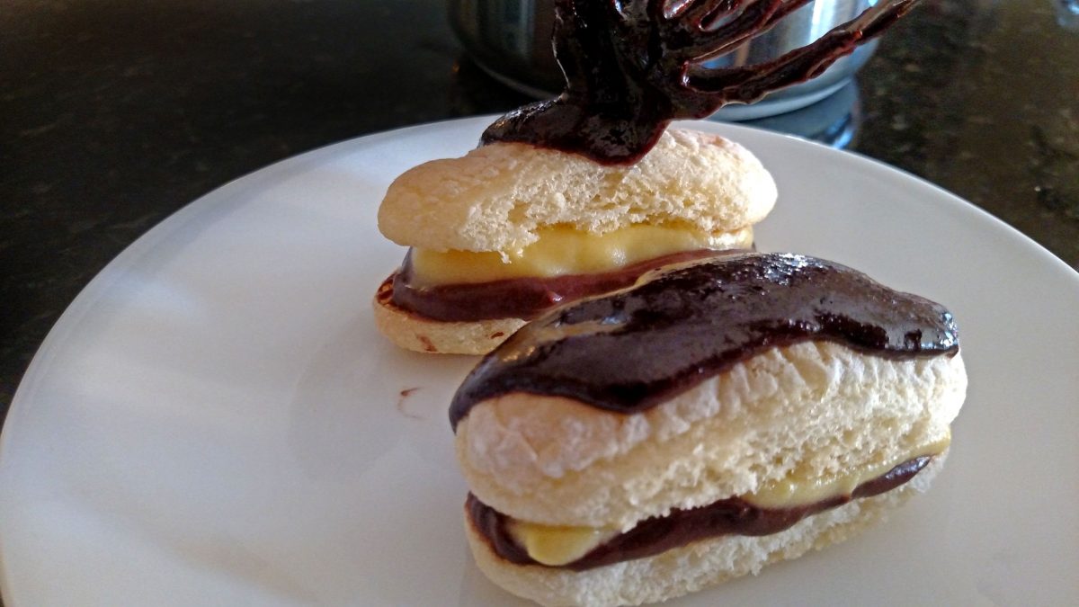 spooning chocolate onto eclair