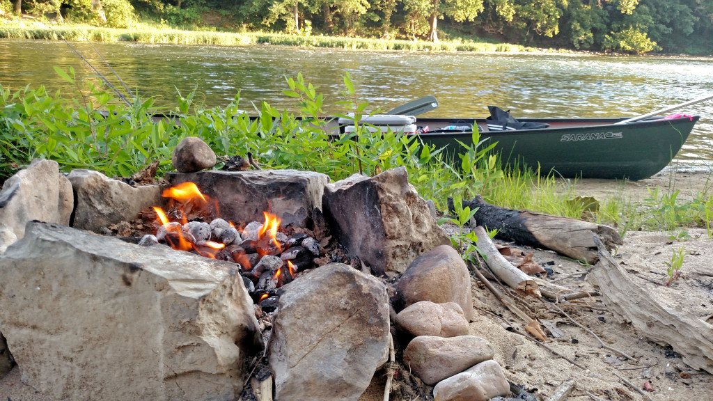 canoe by river with camp fire on the bank