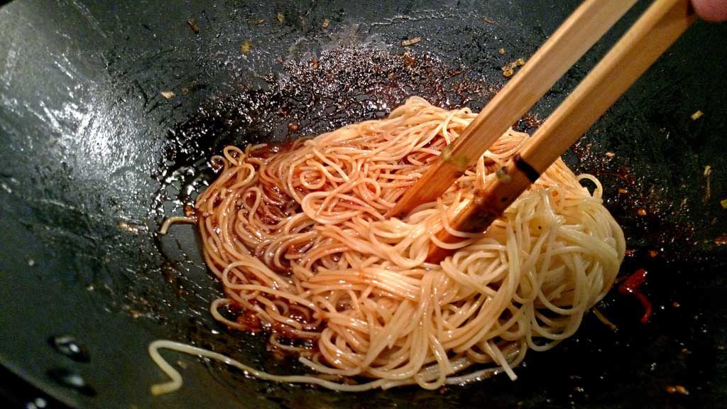 pasta cooking in wok with sauce