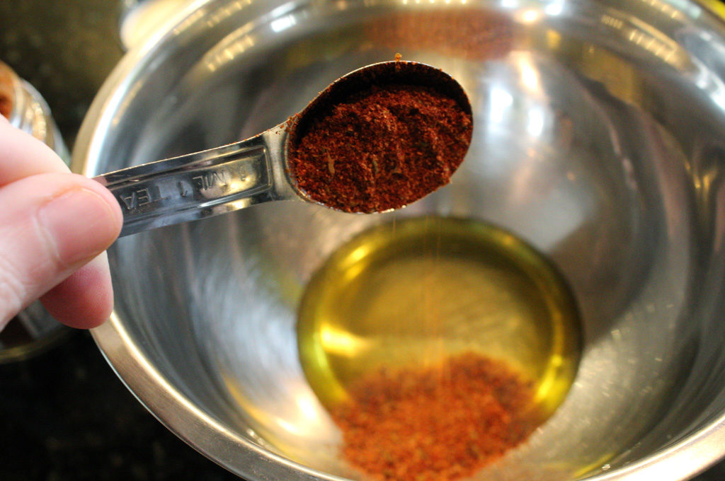 adding seasoning to oil in bowl