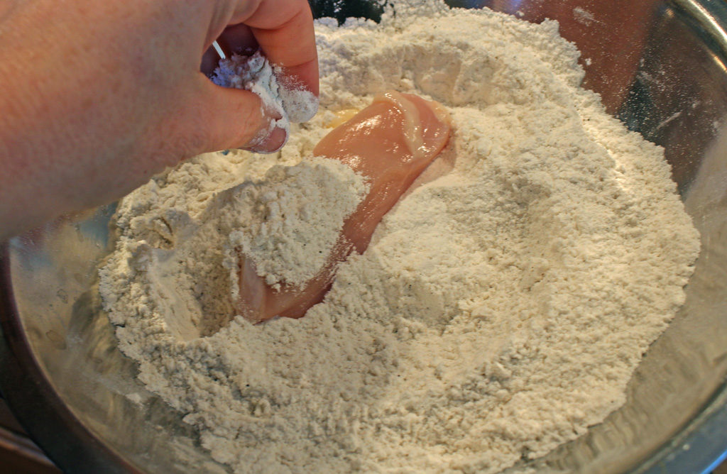 dipping egg coated chicken into breader