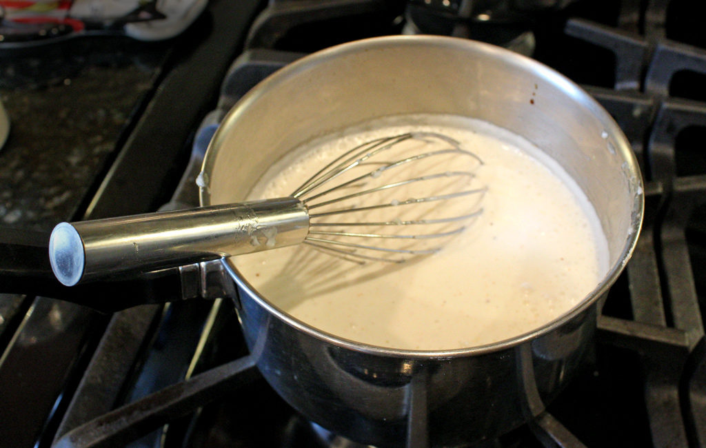 white bbq dipping sauce in pot on stove with whisk