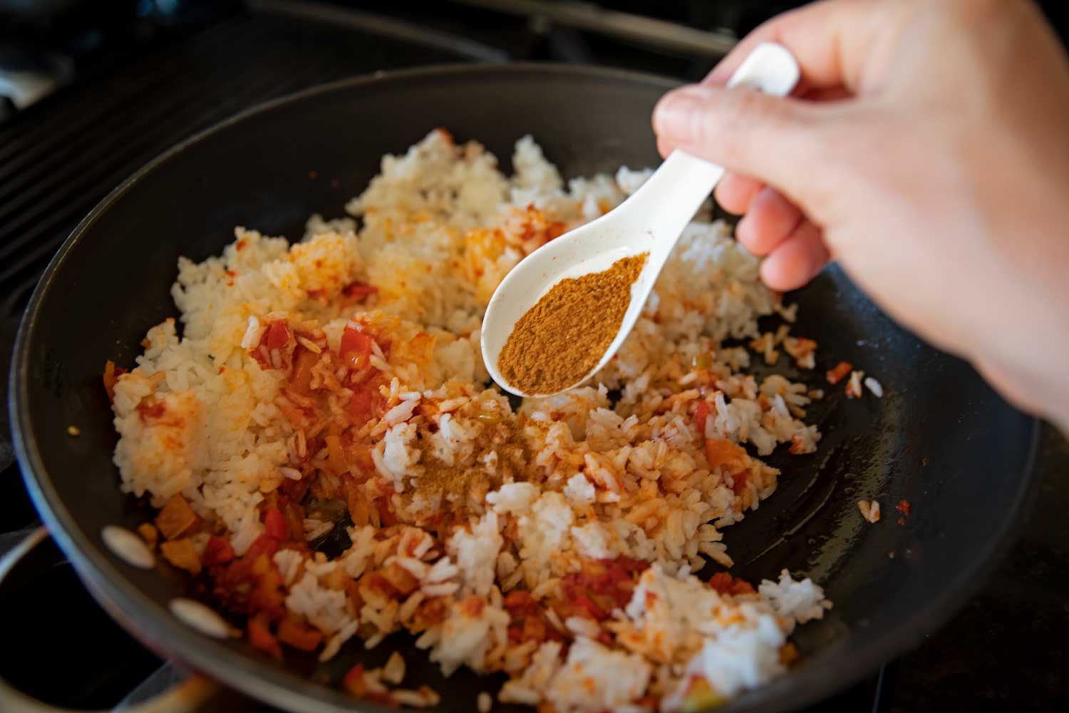 adding seasoning to pan of ingredients