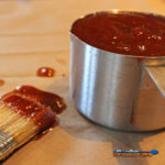 classic barbecue sauce in measuring cup with messy basting brush