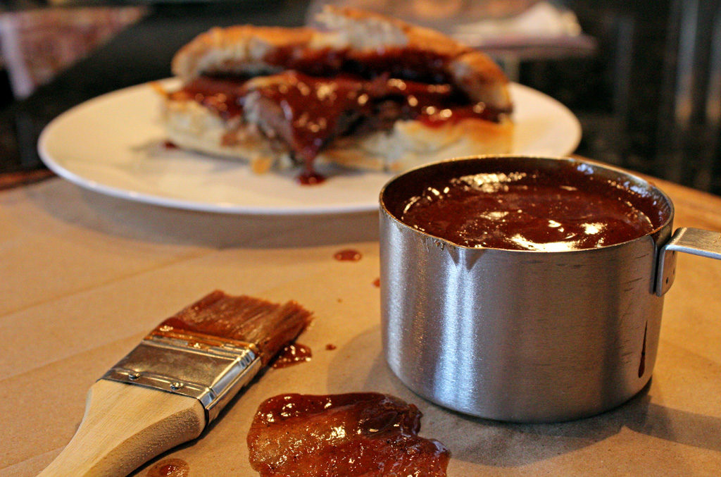 classic barbecue sauce in measuring cup with basting brush