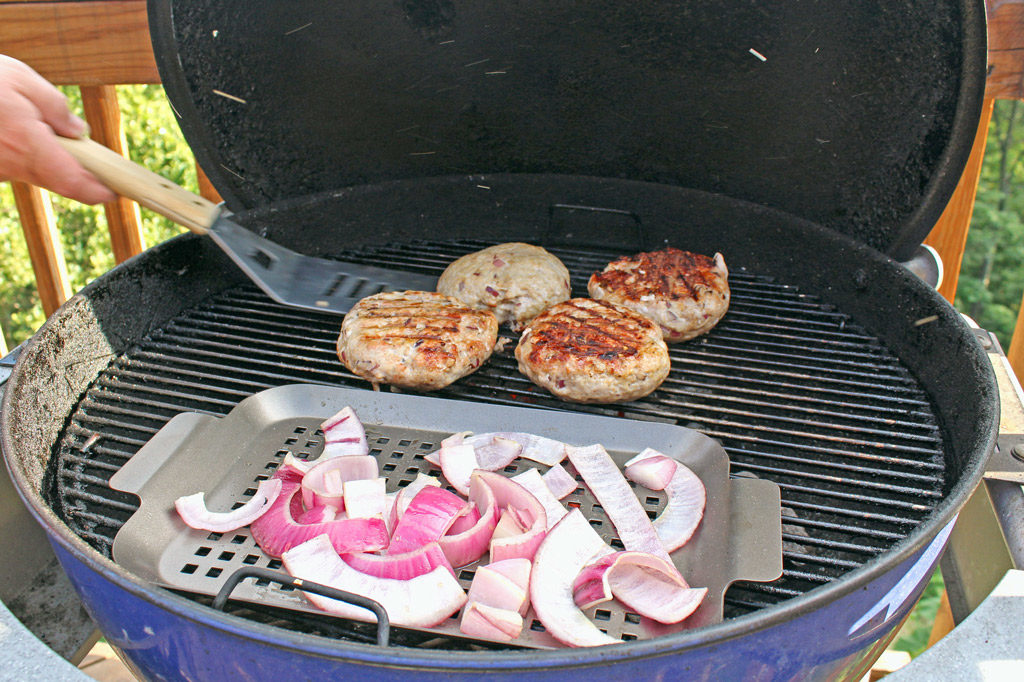 flipping burgers on grill with onions