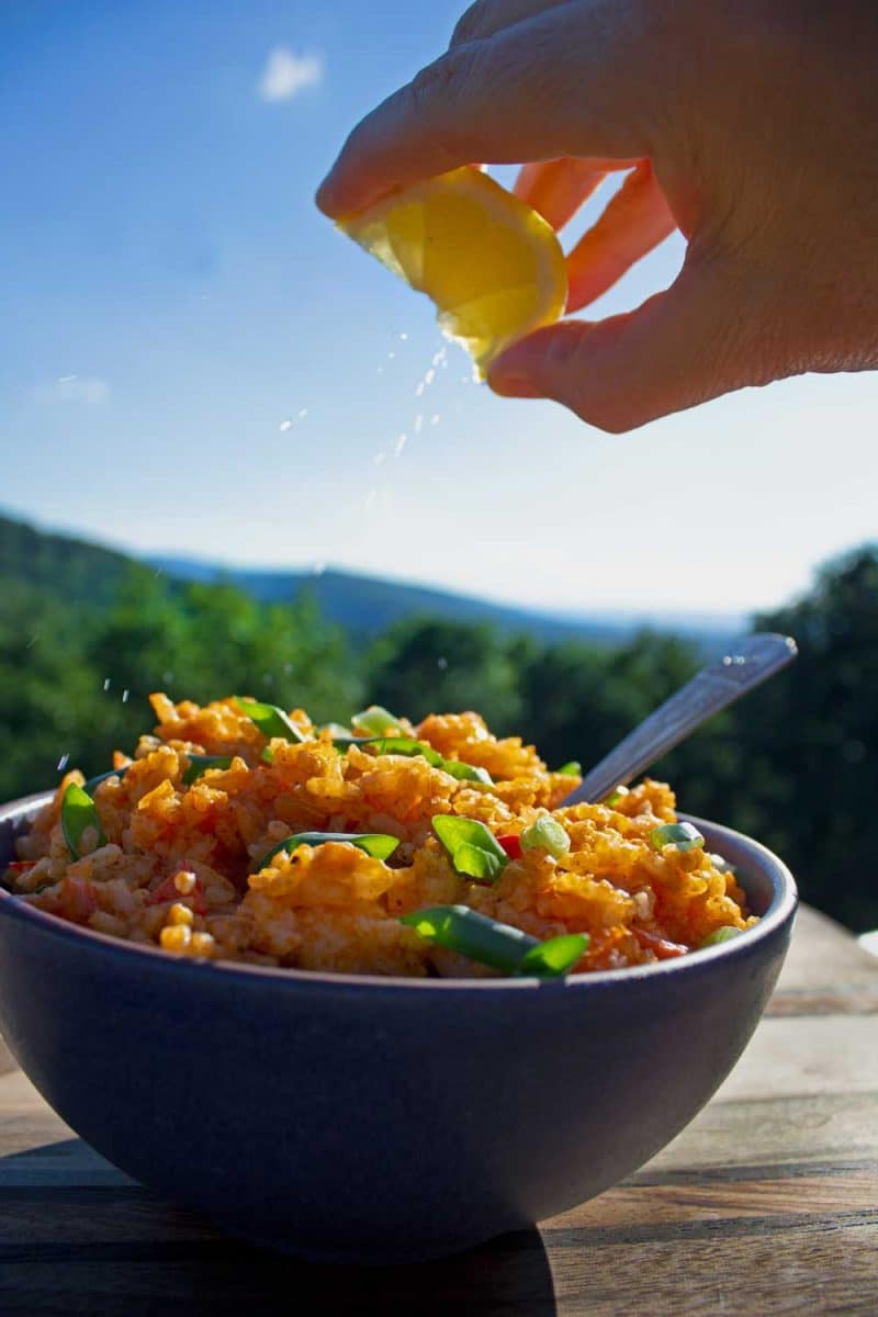 squeezing lemon juice onto bowl of Cajun rice