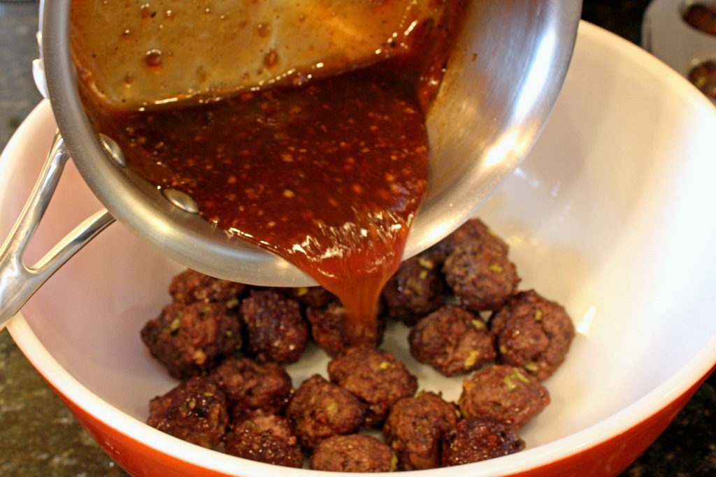 pouring sauce onto meatballs