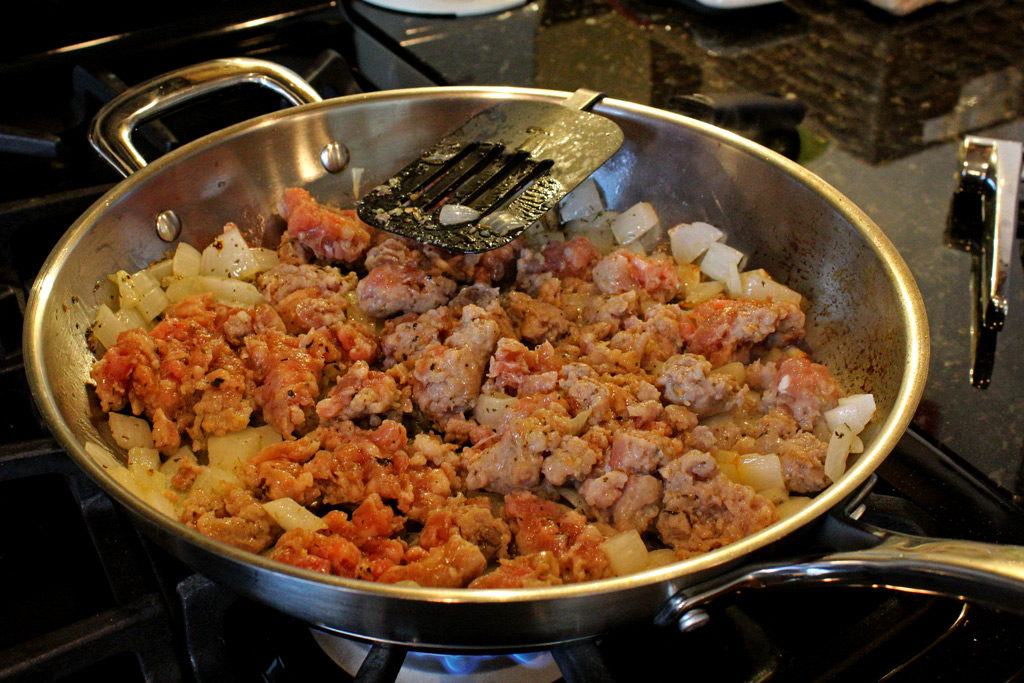 sausage and onions cooking in a pan