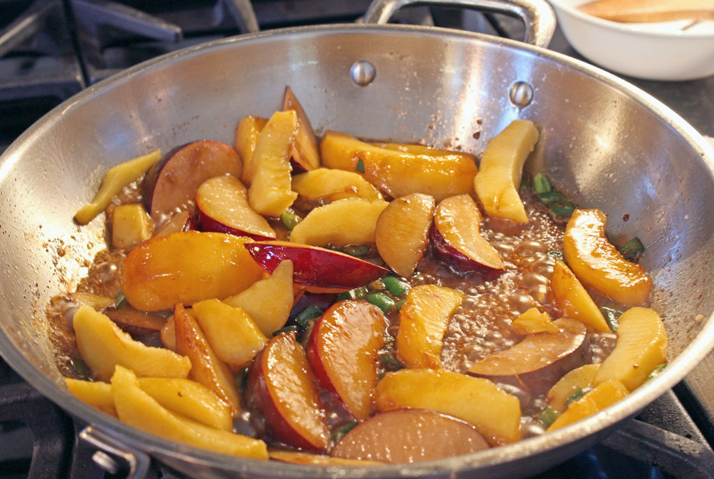 plums and peaches cooking in pan
