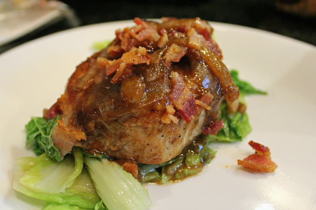 pan seared pork chop with dijon bacon vinaigrette served on top of cabbage