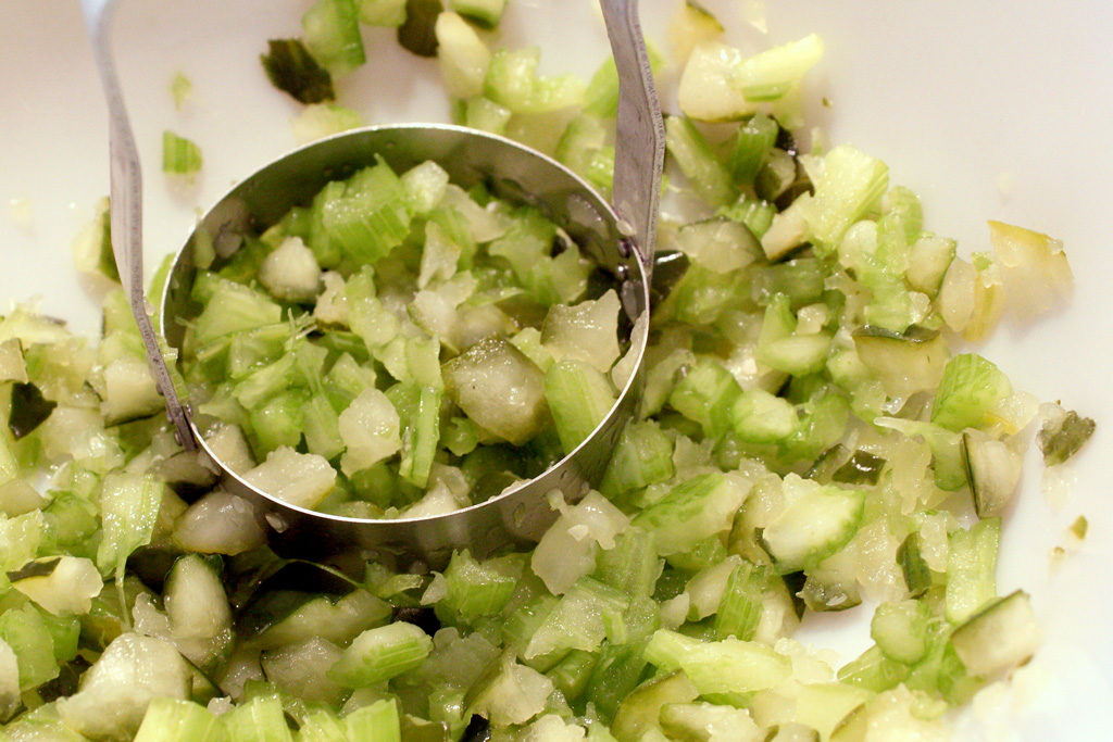 chopped pickle relish in bowl with hand-held chopper