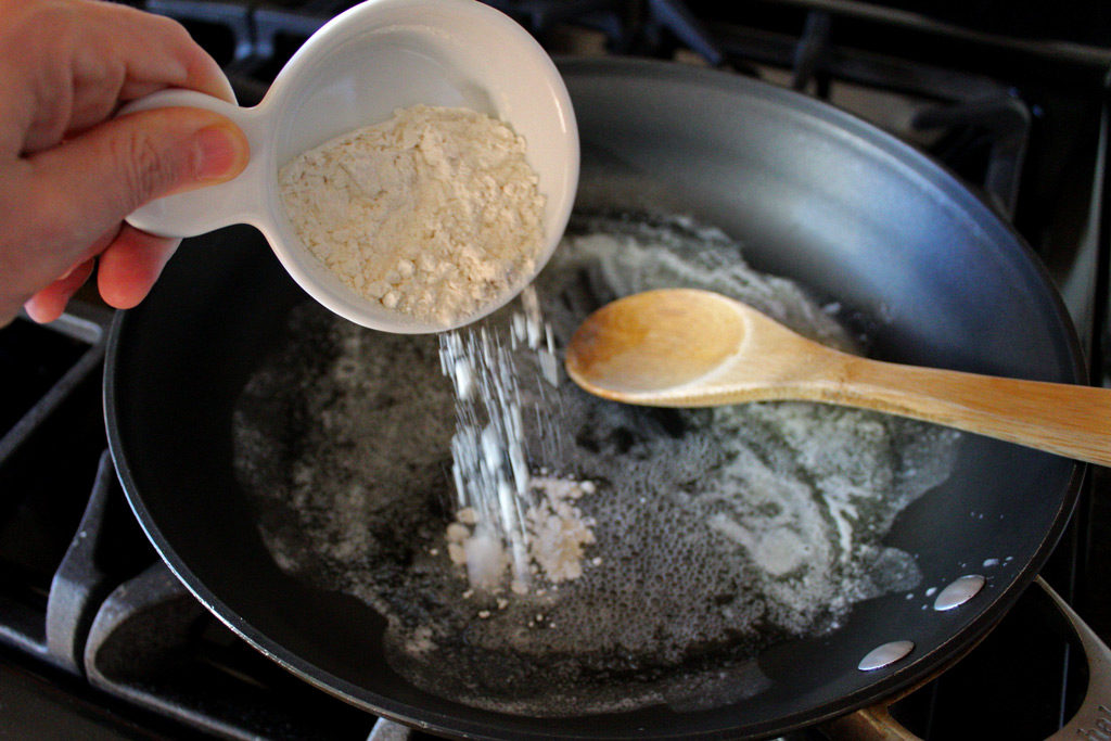 pouring flour into butter in skillet