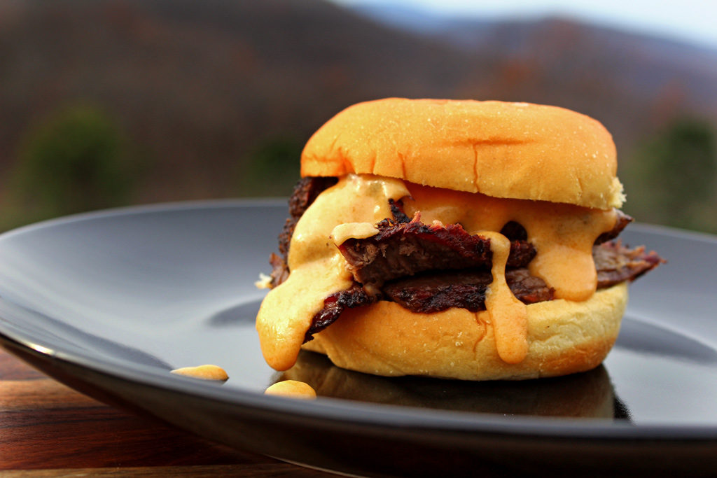 chuck roast sandwich with cheese sauce oozing out of it
