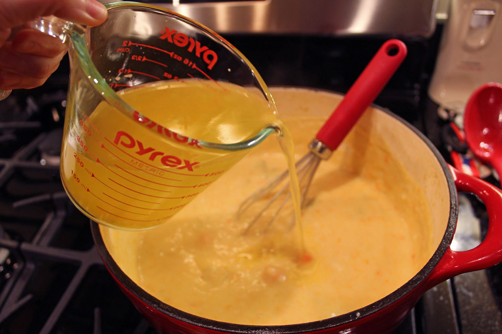 measuring cup pouring broth into pot