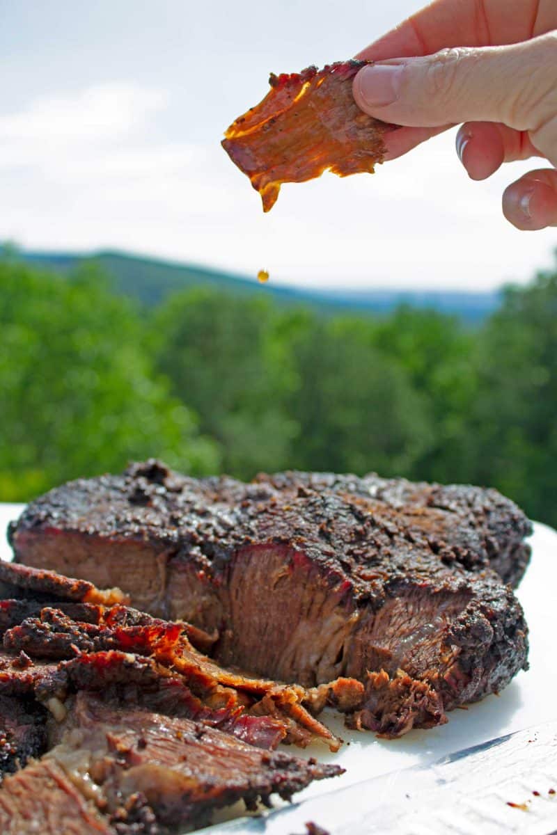 hand holding dripping meat over cutting board
