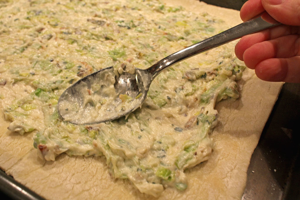 smearing ricotta cheese and leeks onto pastry