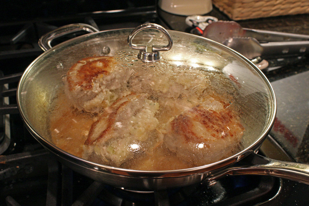 skillet with lid on cooking pork chops