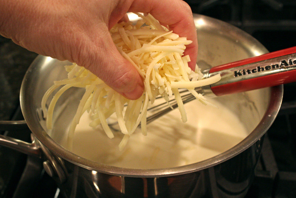 adding cheese to the cream sauce