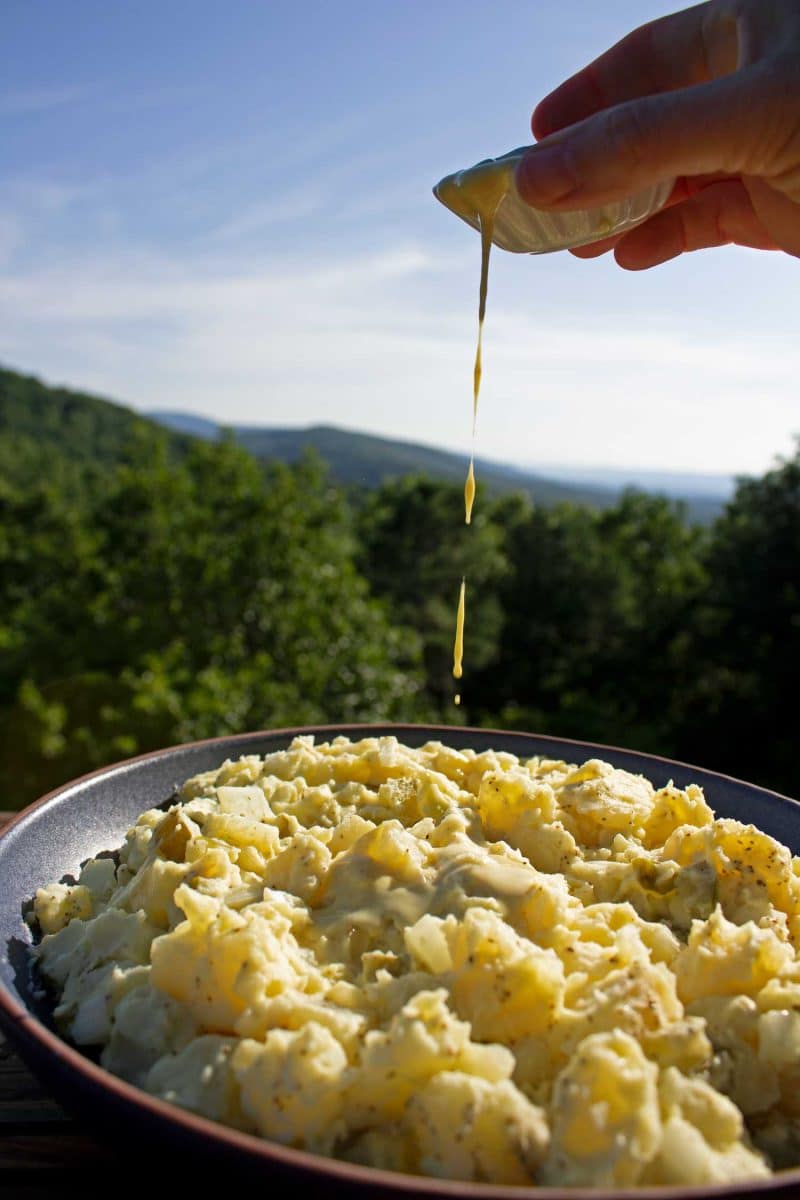 drizzling dressing over potato salad