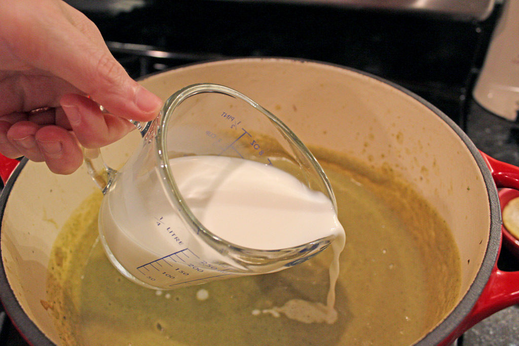 pouring in milk into soup