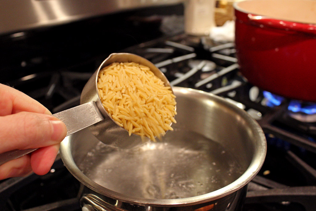 cup of orzo going into pot of boiling water