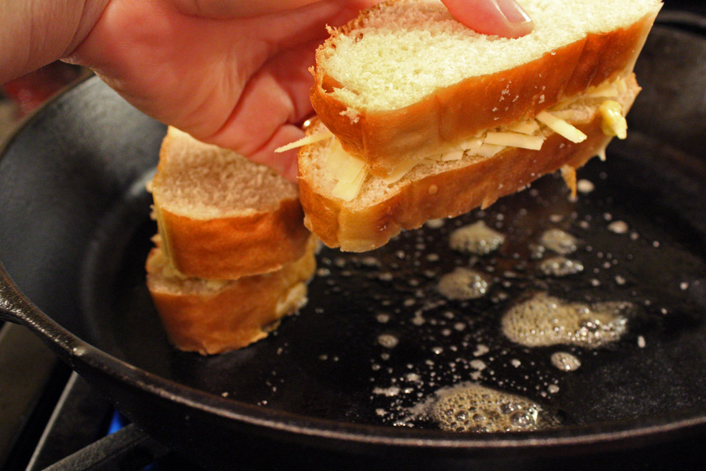 placing grilled cheese into pan