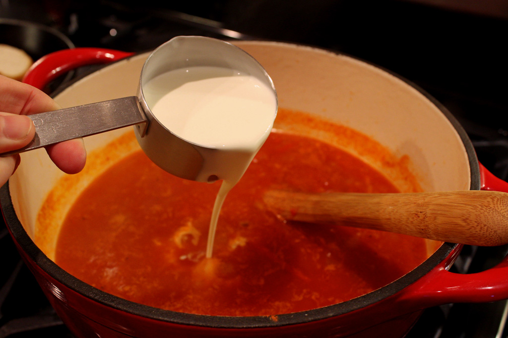 pouring cream into tomato orzo soup
