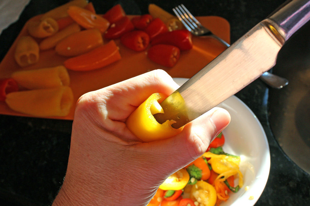 inserting knife into mini pepper to remove veins and seeds