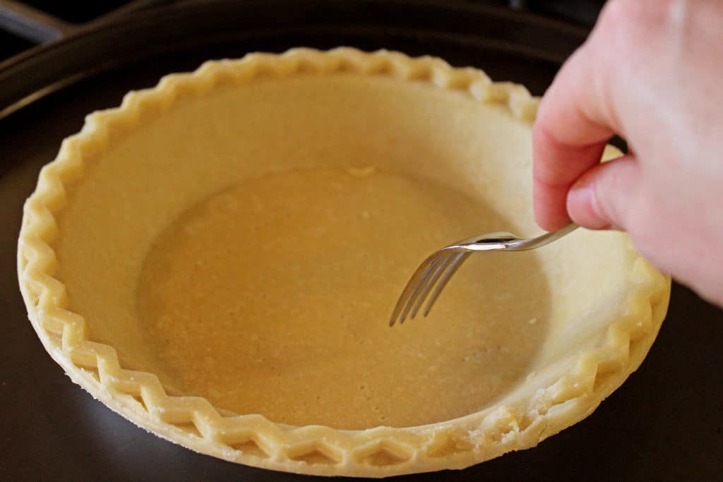 sticking fork into bottom of pie crust